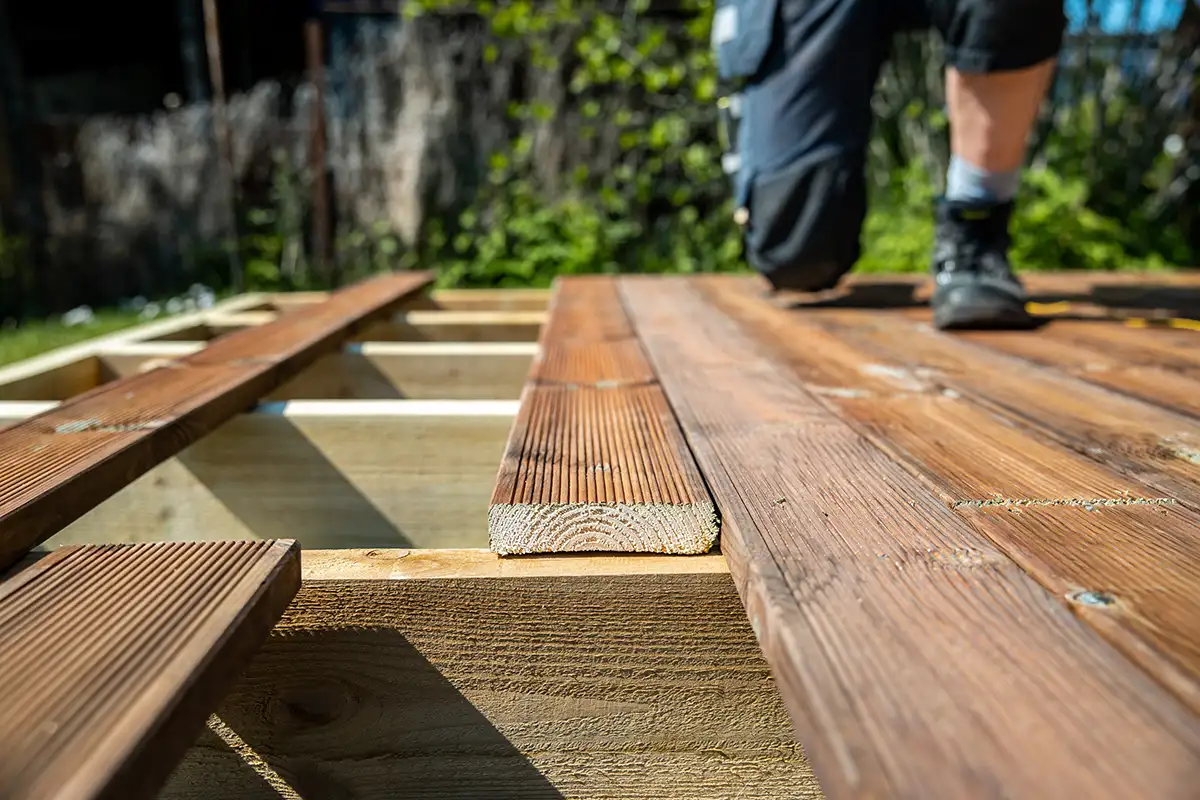 sgd - Entwässerung und Gefälle korrigieren Mann bei der Reparatur Holzterrasse