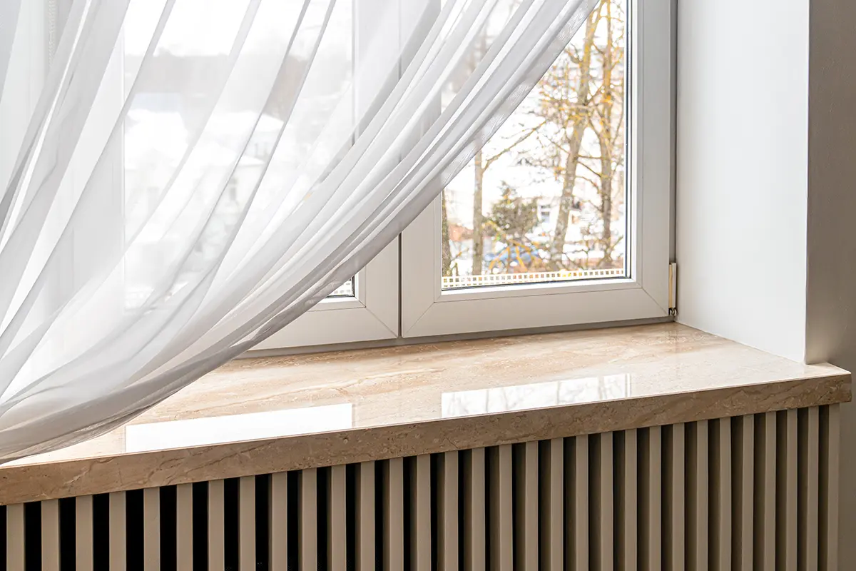 sgd - Fensterbänke aus Naturstein Fensterbank aus Naturstein mit einem leichten Vorhang vor dem Fenster.