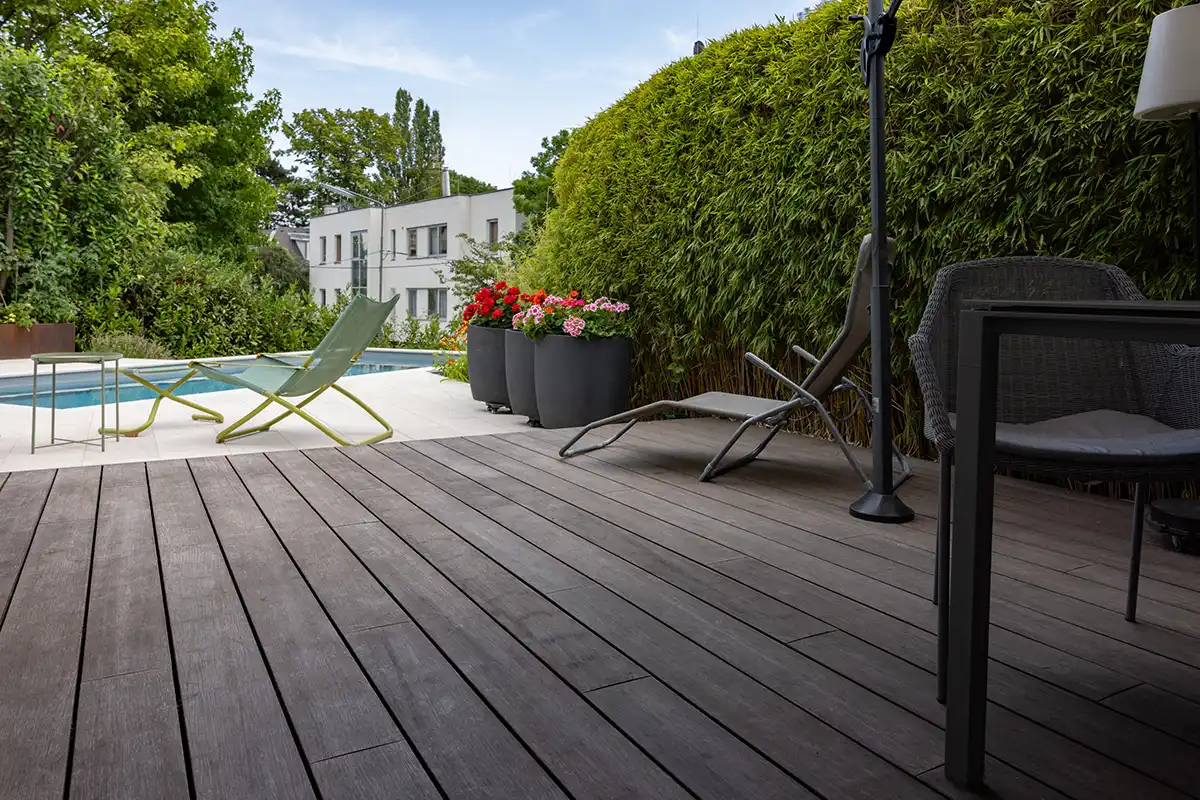 sgd - Premium-Werkstoffe für Generationen Eine Terrasse mit einem Tisch, Stühlen und einem Pool im Hintergrund