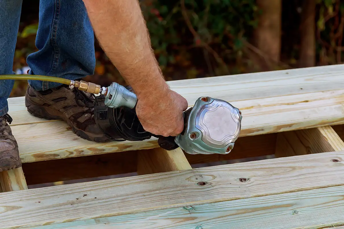 sgd - Reparatur der Dielenoberfläche Mann arbeitet mit Bohrmaschine an der Reparatur Decks