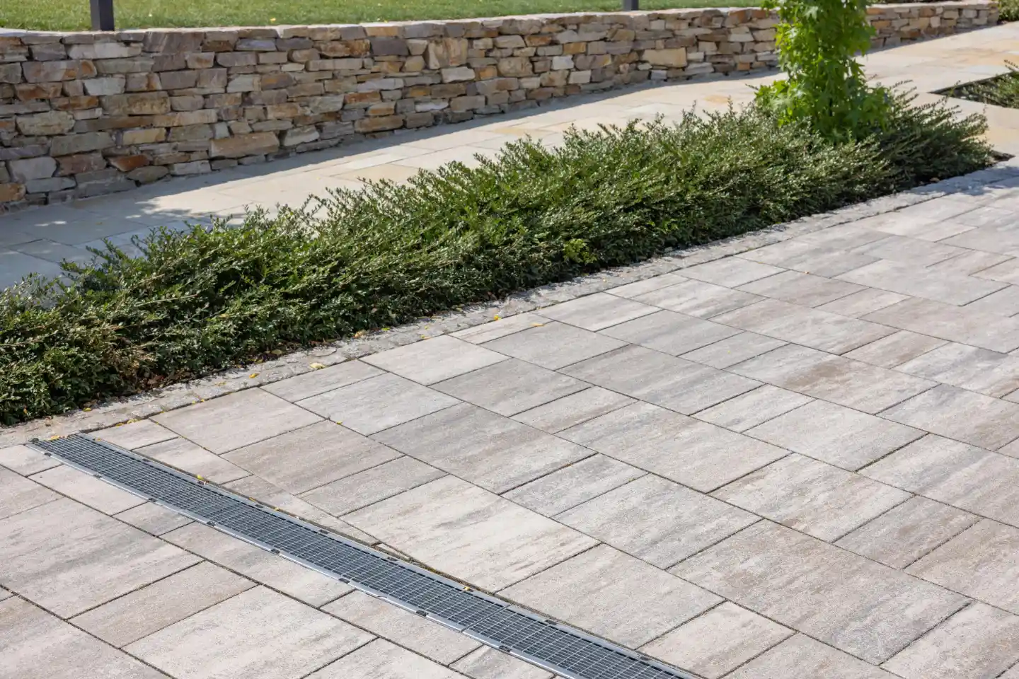 Professionelle Renovierung des Hofes: ebene Pflasterung mit Fliesen und Installation von Regenwasserableitungssystemen.